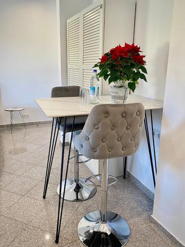 uma mesa com uma cadeira e um vaso com flores vermelhas em Zentrale, neue Wohnung in Bamberg mit kostenlosen Parkplätzen vor Ort em Bamberg