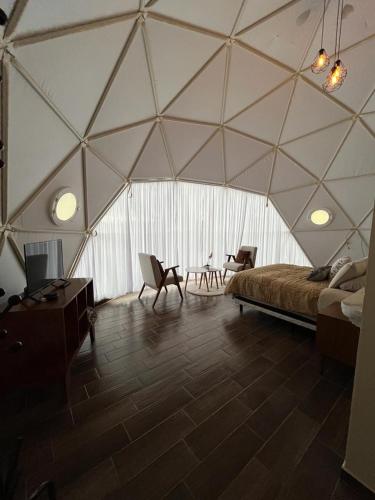 a tent with a bed and chairs in a room at El Gato Glamping con vista al valle in Huasca de Ocampo