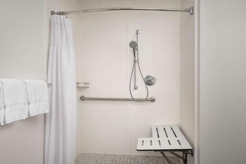 y baño con ducha con cortina de ducha y banco. en Courtyard by Marriott Dothan en Dothan