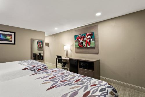 a bedroom with a bed and a desk and a tv at Red Roof Inn Redding in Redding