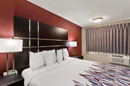 a large bed in a hotel room with red walls at Red Roof Inn Redding in Redding