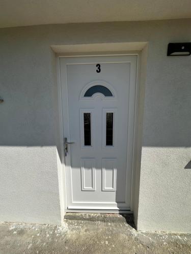 a white door with the number three on it at Apartmani Tamaris in Murter