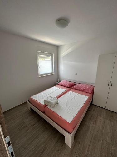 a bedroom with a bed with red and white sheets at Apartmani Tamaris in Murter