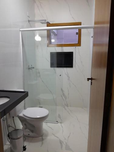 a bathroom with a toilet and a glass shower at Pousada Vivenda in Olímpia