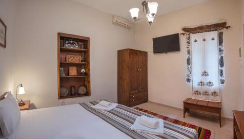 a bedroom with a bed and a tv on the wall at Feneri Traditional House Apt 1- 20' from Elafonisi beach in Perivólia