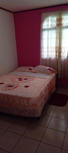 ein kleines Bett in einem Zimmer mit Fenster in der Unterkunft Apartamentos HJJ in Puerto Limón