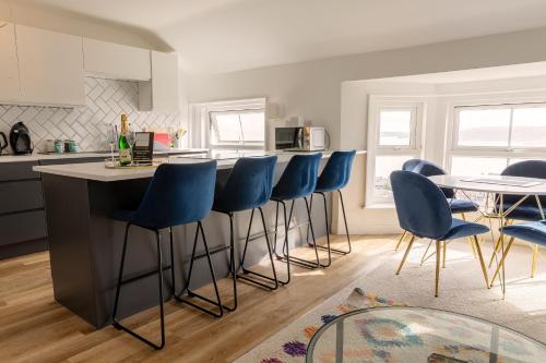 a kitchen with blue bar stools and a table at Seabourne Scarborough Beautiful 2 bedroom 2 bathrooom Penthouse With Fabulous Seaview in Scarborough