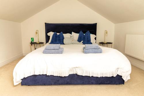 een slaapkamer met een groot wit bed met blauwe kussens bij Seabourne Penthouse Stunning Seaviews with optional hot tub hire at Homesweetholidayhomes in Scarborough