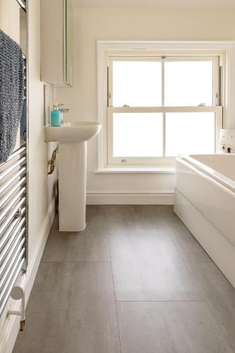 a white bathroom with a sink and a window at Seabourne Penthouse Stunning Seaviews with optional hot tub hire at Homesweetholidayhomes in Scarborough
