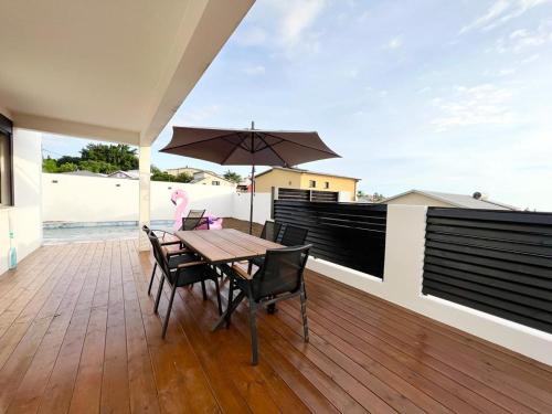 a wooden deck with a wooden table and an umbrella at Villa Moderne et Piscine Privée in Saint-Pierre