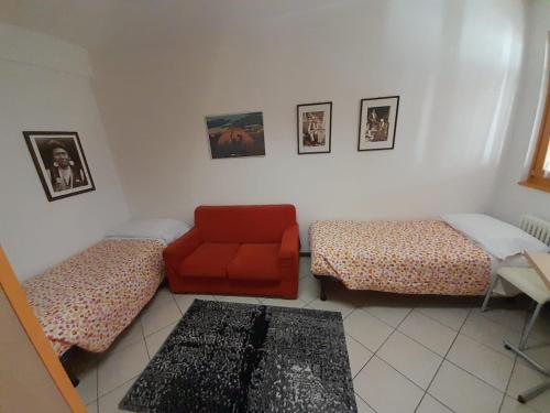 a living room with two beds and a red couch at Lunga Via Delle Dolomiti in Calalzo