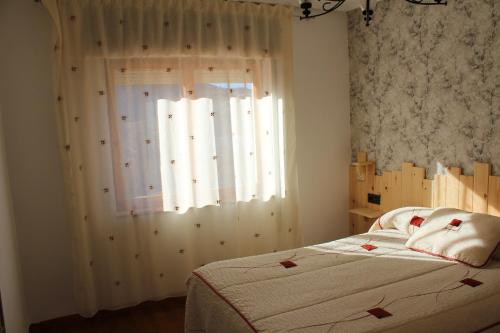 1 dormitorio con 1 cama y una ventana con cortinas blancas en casa en la montaña leonesa, en Santa Lucia