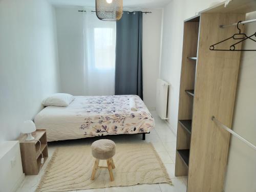 a small bedroom with a bed and a stool at KEZA's Apartment - Strasbourg in Strasbourg