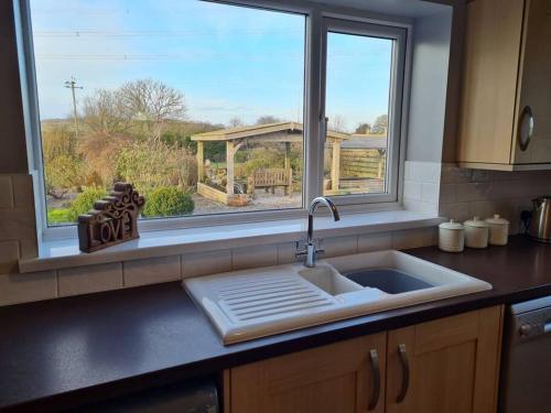 a kitchen counter with a sink and a window at Romantic rural cottage, log burner, Sky tv early check in ,large gardens in Llangefni