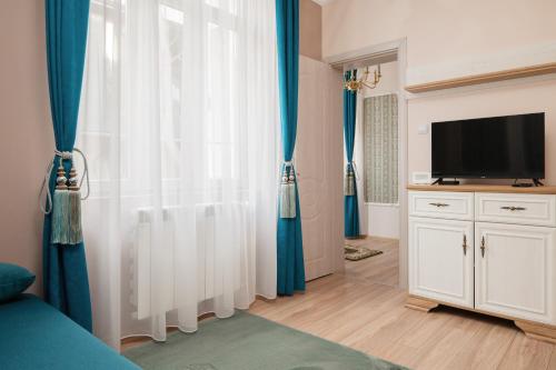 1 dormitorio con cortinas azules y TV en Serdika Old City House en Sofía