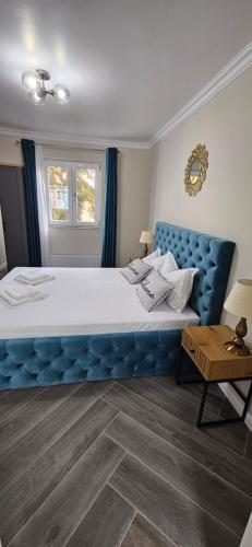 een groot bed met een blauw hoofdeinde in een slaapkamer bij White rezidence II in Curtea de Argeş