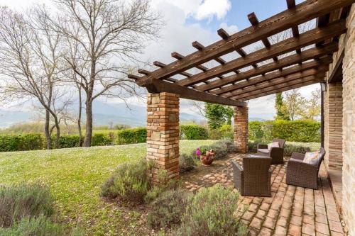a brick patio with chairs and a wooden pergola at Luxury Villa with Pool, Stunning Location in San Ginesio