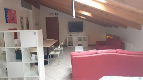 a living room with a pink couch and a table at Lunga Via Delle Dolomiti in Calalzo