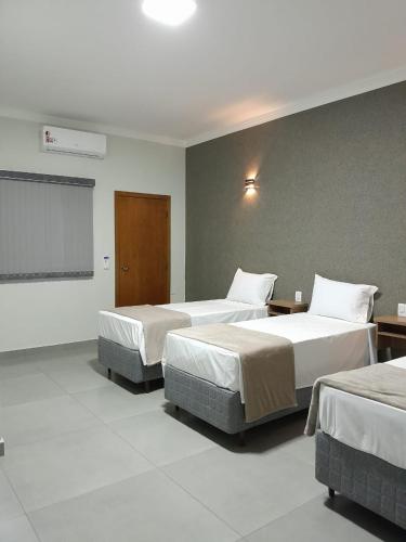 a hotel room with two beds and a projection screen at Pousada Vivenda in Olímpia