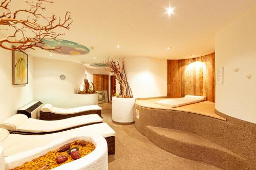 a hotel room with two beds and a bathtub at Hotel Hofmann in Santa Maddalena in Casies