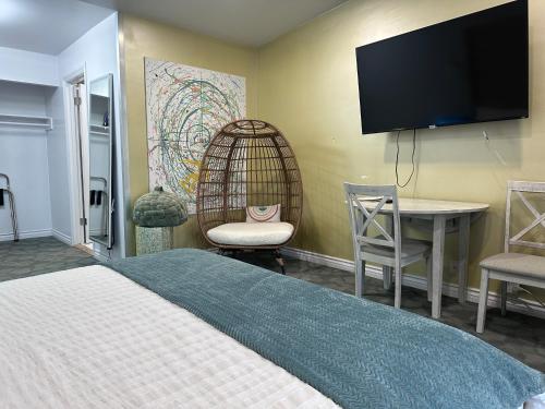 a bedroom with a bed and a desk and a tv at Foghorn Harbor Inn in Los Angeles