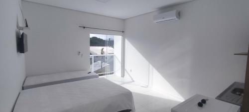 a white bedroom with a bed and a window at Recanto do Valtinho in Florianópolis