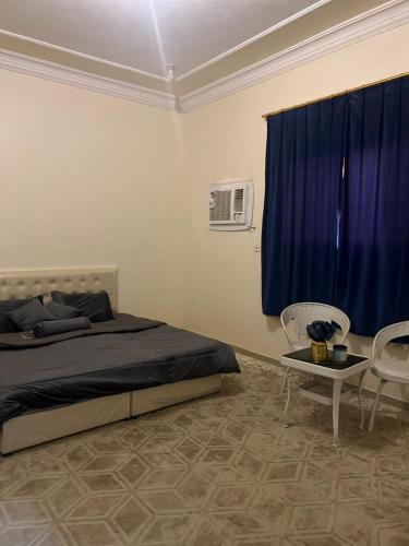 شقق وغرف خاصة في حائل: غرفة نوم بسرير وطاولة وستارة زرقاء