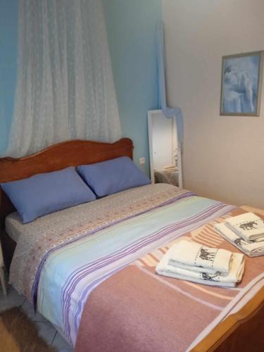 Una cama con almohadas azules y toallas. en Φιλόξενο σπίτι στο Λουτράκι! en Loutraki