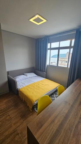 a bedroom with a bed and two yellow chairs at Dias na Praia in São Vicente