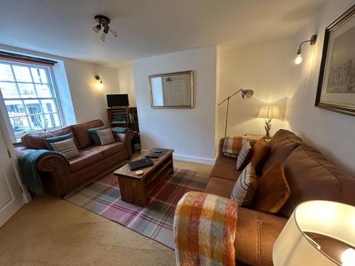 ein Wohnzimmer mit einem Sofa und einem Tisch in der Unterkunft Jacobite's Retreat, 17th century cottage in the heart of Inverness in Inverness