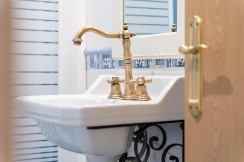 a bathroom sink with two gold faucets in front of a mirror at Casa Maza Apartamentos in Biescas