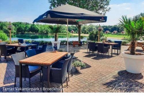 a patio with tables and chairs and an umbrella at Gezellig 6pers Familiehuis grote tuin met BBQ aan meer Gelderland in Ewijk
