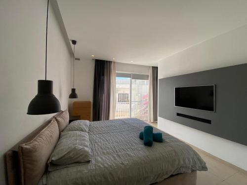 Un dormitorio con una cama con un televisor en la pared. en St Julians Apt with Pool, en San Julián