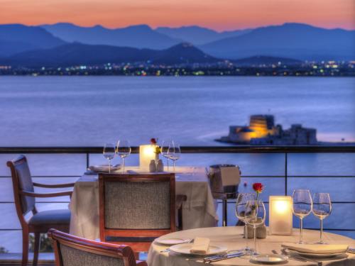 a table with wine glasses and a view of the water at Nafplia Palace Hotel & Villas in Nafplio