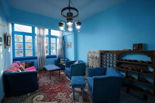 a blue room with blue chairs and a child sleeping on a couch at Rose Apartments in Nag` el-Ramla