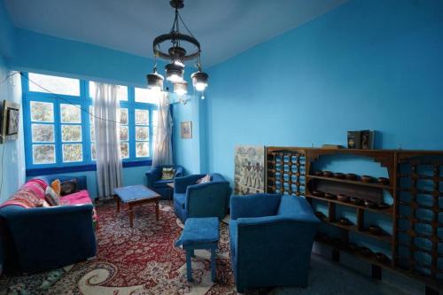 a living room with blue walls and blue chairs at Rose Apartments in Nag` el-Ramla