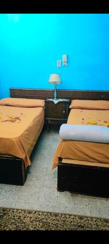two beds in a room with a blue wall at Rose Apartments in Nag` el-Ramla