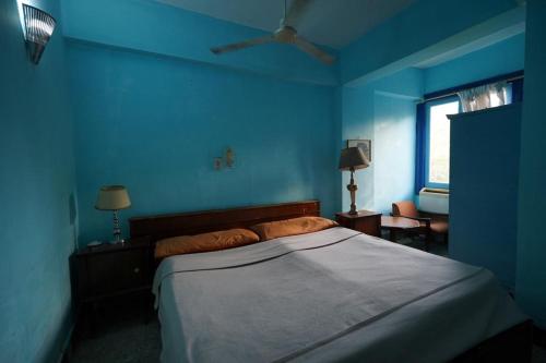 a blue bedroom with a bed and a window at Rose Apartments in Nag` el-Ramla