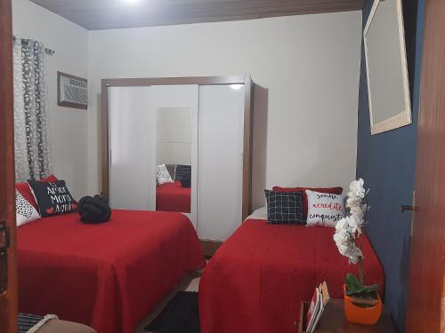 a bedroom with two beds with red sheets and a mirror at Casa Azul-Paraíso em Búzios in Búzios