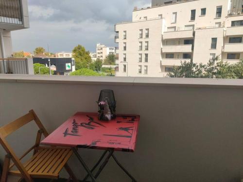 d'une table rouge et d'une chaise sur un balcon. dans l'établissement Appartement in Villejuif (M 7) with free parking, à Villejuif