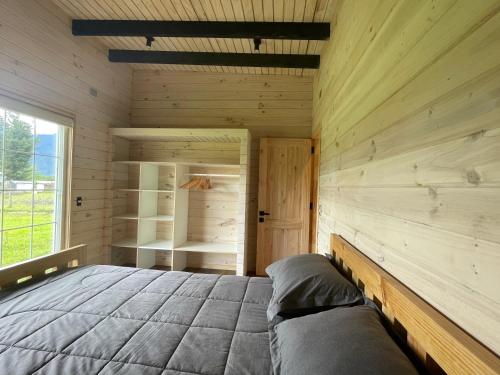 Blockhausschlafzimmer mit einem Bett und einem Fenster in der Unterkunft Cabaña Azul in Riñinahue