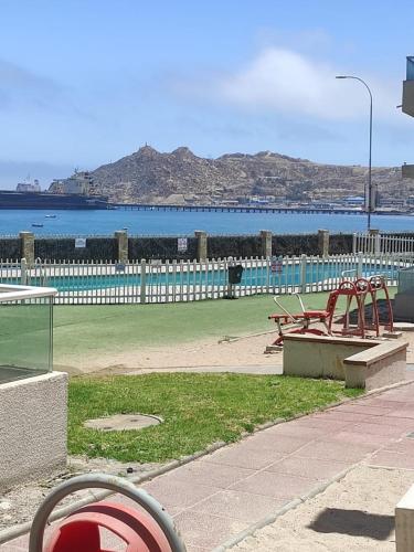 a park with two benches and the ocean in the background at Duplex la herradura in Coquimbo