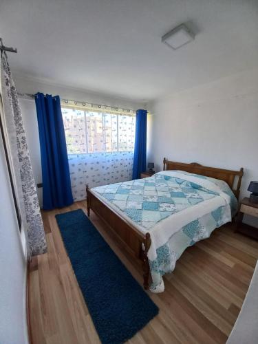 a bedroom with a bed and a window with blue curtains at Excelente ubicación in Concón