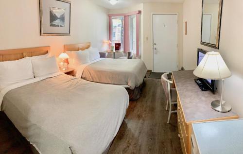 ein Hotelzimmer mit 2 Betten und einem Schreibtisch in der Unterkunft Sunwapta Falls Rocky Mountain Lodge in Jasper