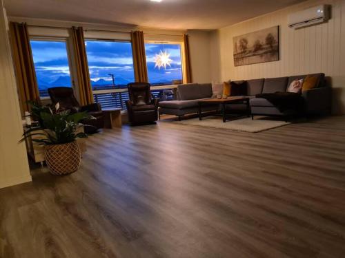 Tromsø stunning Luxury apart B في ترومسو: غرفة معيشة مع أريكة وكراسي ونوافذ