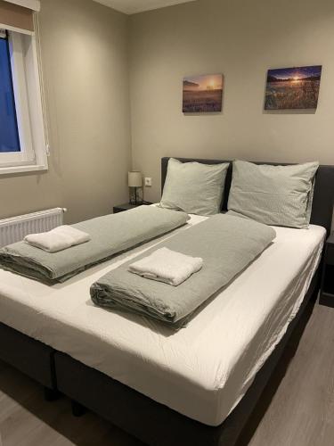 a large bed with two towels on top of it at Kindvriendelijk luxe chalet in de bossen met privé sauna in Harderwijk