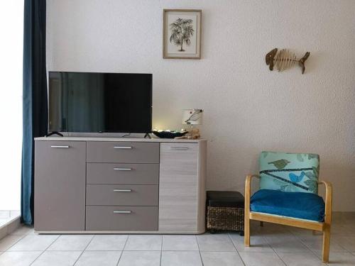 un centro de entretenimiento con TV y silla en Appartement Centre port 4 pers Cap d'Agde en Cap d'Agde