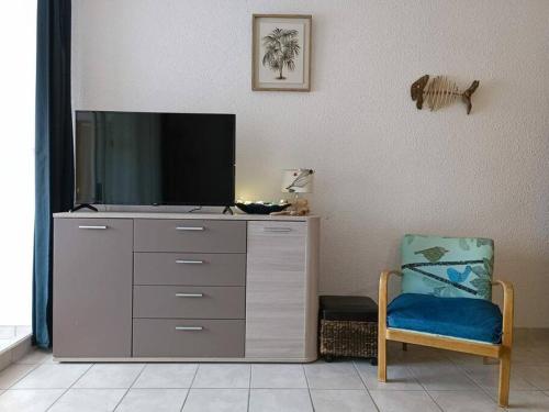 a entertainment center with a tv and a chair at Appartement Centre port 4 pers Cap d'Agde in Cap d'Agde