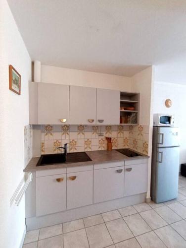 een keuken met witte kasten en een koelkast bij Appartement Centre port 4 pers Cap d'Agde in Cap d'Agde
