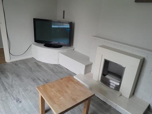 a living room with a tv and a fireplace at Amazing 3 bedroom house with parking. in Nottingham